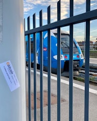 a blue train is parked next to a fence