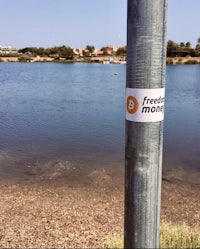 a pole with a sticker on it next to a body of water